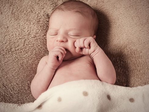 bambino di pochi giorni con dito in bocca