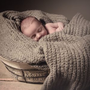 newborn in una cesta adagiato in una sciarpa di lana