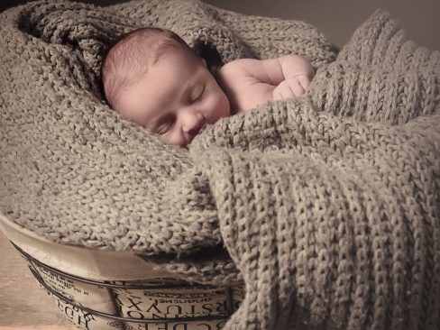 newborn in una cesta adagiato in una sciarpa di lana