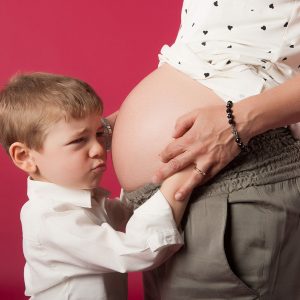 donna incinta che tiene per mano un bimbo imbronciato