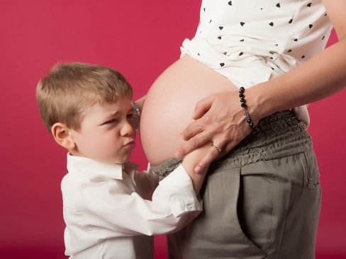 donna incinta che tiene per mano un bimbo imbronciato