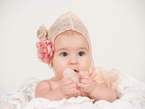 bimba su una nuvola bianca di pochi mesi con cuffietta in pizzo e fiore rosa