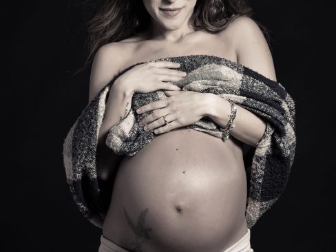 bellissima donna incinta, capelli lunghi, sguardo sensuale e tatuaggio sulla pancia