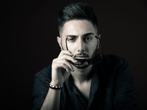 ragazzo occhi a mandorla, labbra carnose, barba corta, occhiali da sole