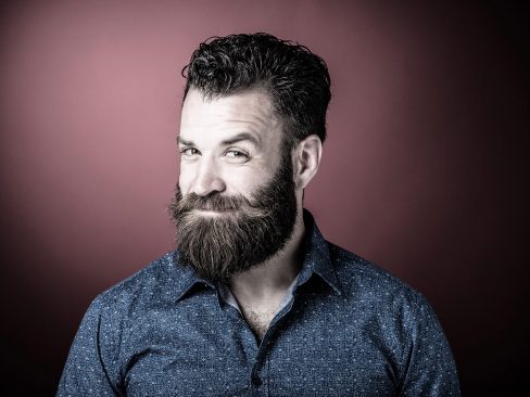 uomo con sguardo furbetto e divertente, barba e baffi molto lunghi